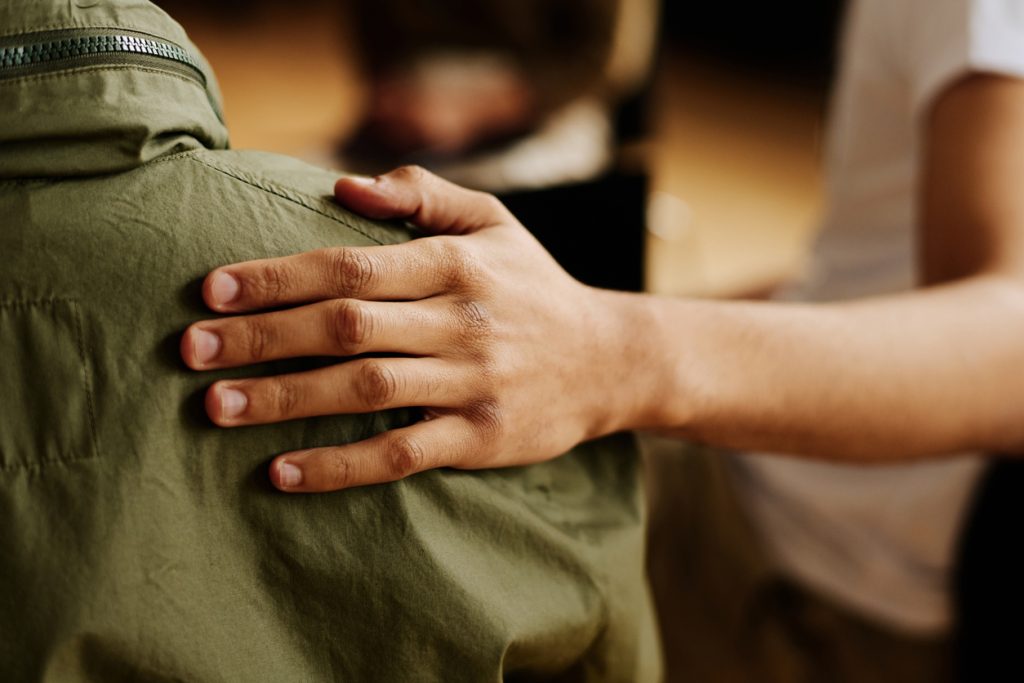 Hand of young supportive man consoling his friend