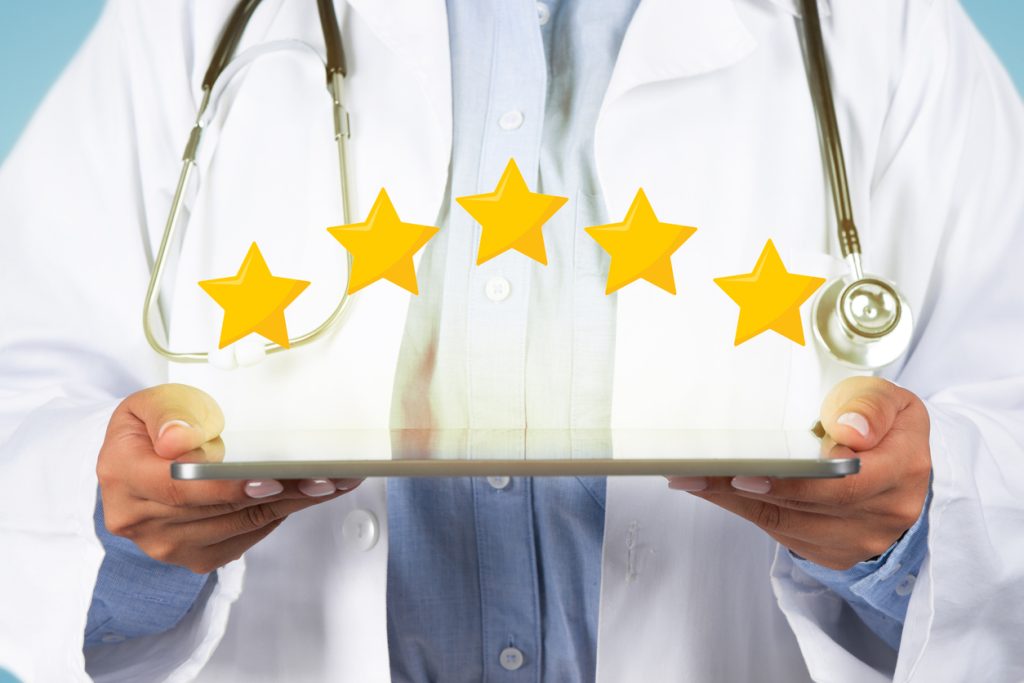 Medical services rating. Unrecognizable young female doctor holding digital tablet with five stars icons above, closeup studio shot, cropped